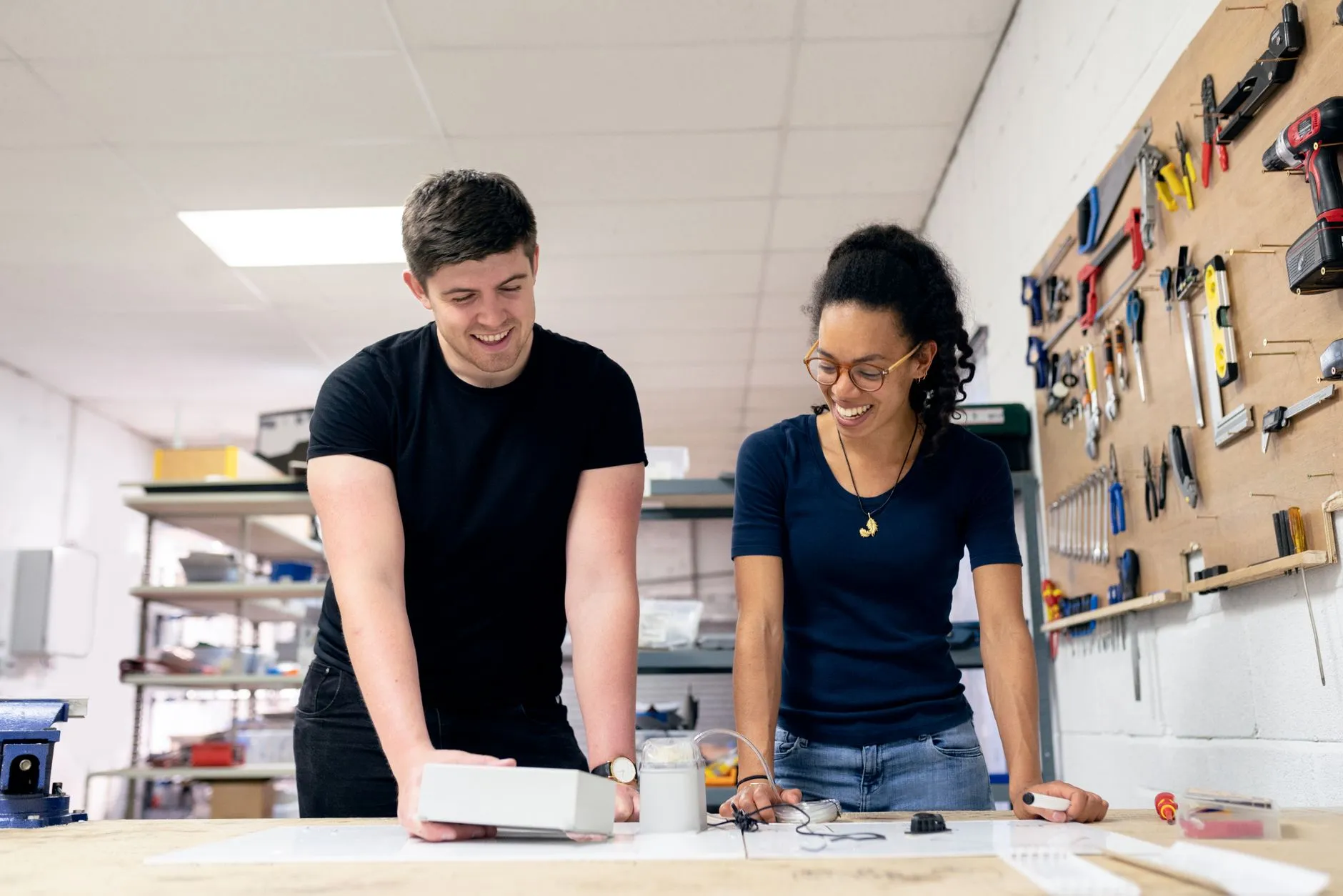 Two people working together on a prototype at a workbench in a workshop