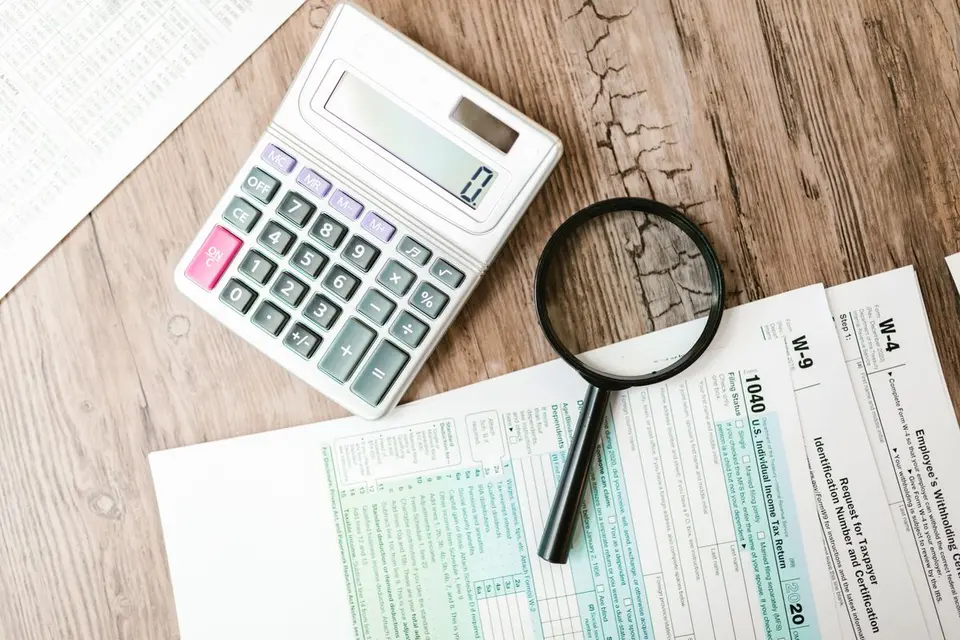 Calculator, magnifying glass and tax forms on a desk